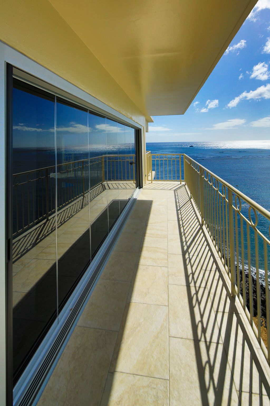 Custom grey glass 22 foot ocean front frameless sliding glass door withretractable Centor screens.